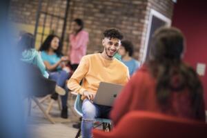 Student sitting in a chair on his laptop smiling
