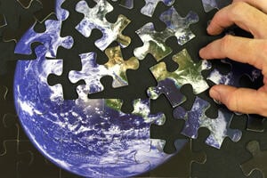 Picture of a person playing with a planet Earth themed jigsaw puzzle.