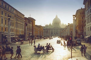 Photograph of a busy street in Rome with St. Peter's Basilica in the distance