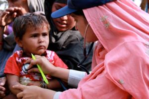A female doctor with the International Medical Corps checking the heartbeat of a young boy with a stethoscope