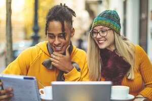 Men and women looking at a screen and sharing notes while smiling